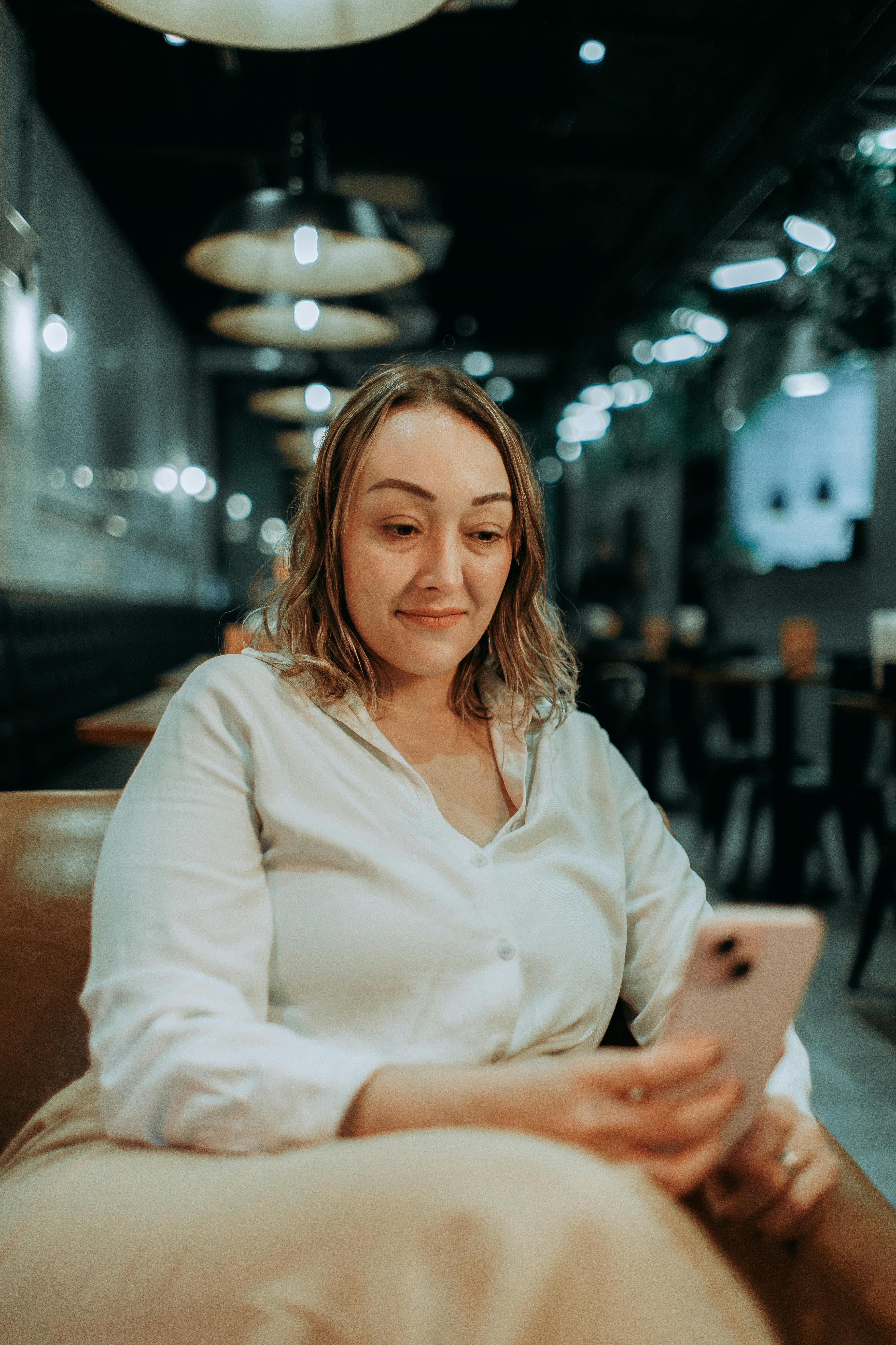 Woman checking her phone in a softly lit evening cafe