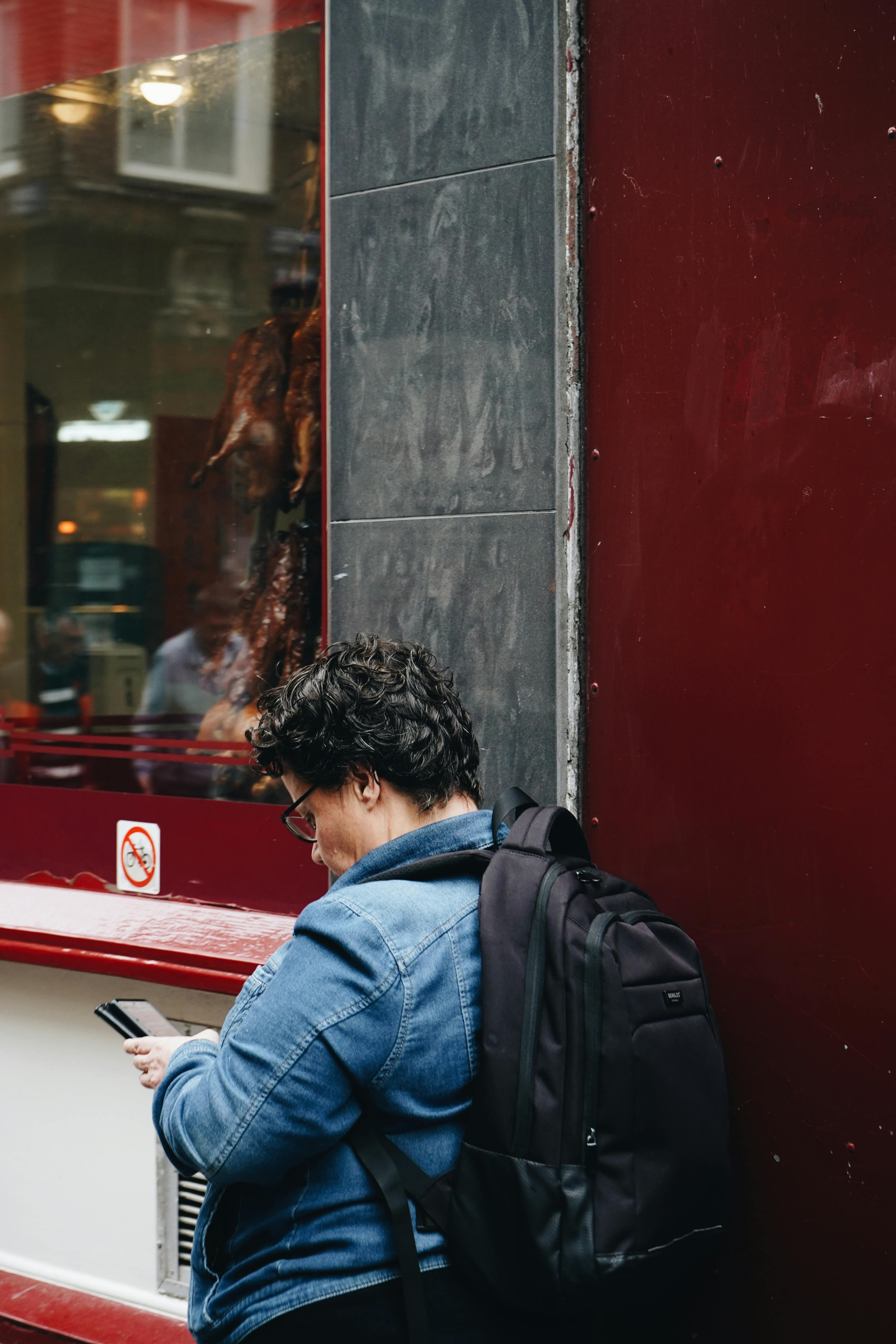 Person standing outside a restaurant while checking a phone
